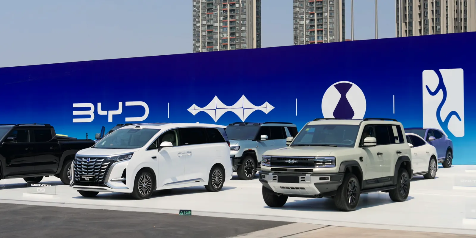 مركبات مجموعة BYD معروضة أمام لافتة BYD، ومنها سيارة Denza D9 متعددة الأغراض وسيارة SUV للطرق الوعرة