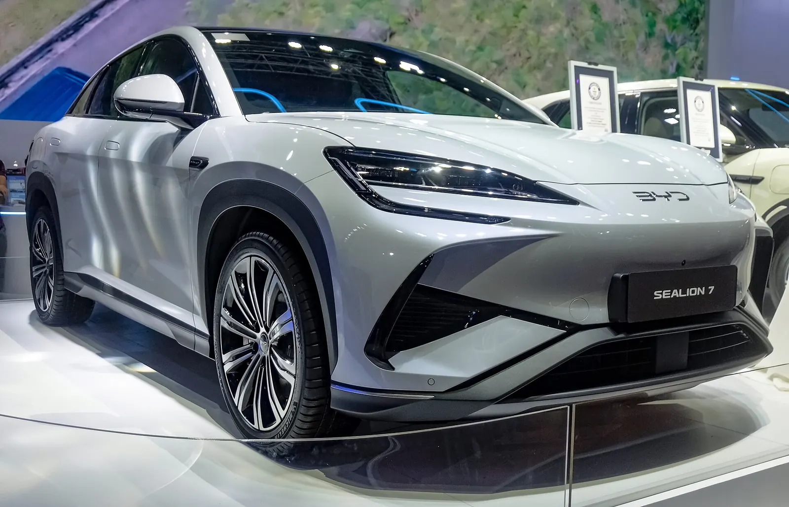Close front three-quarter view of a silver BYD Sealion 7 showing the slim headlights and wheel-arch cladding