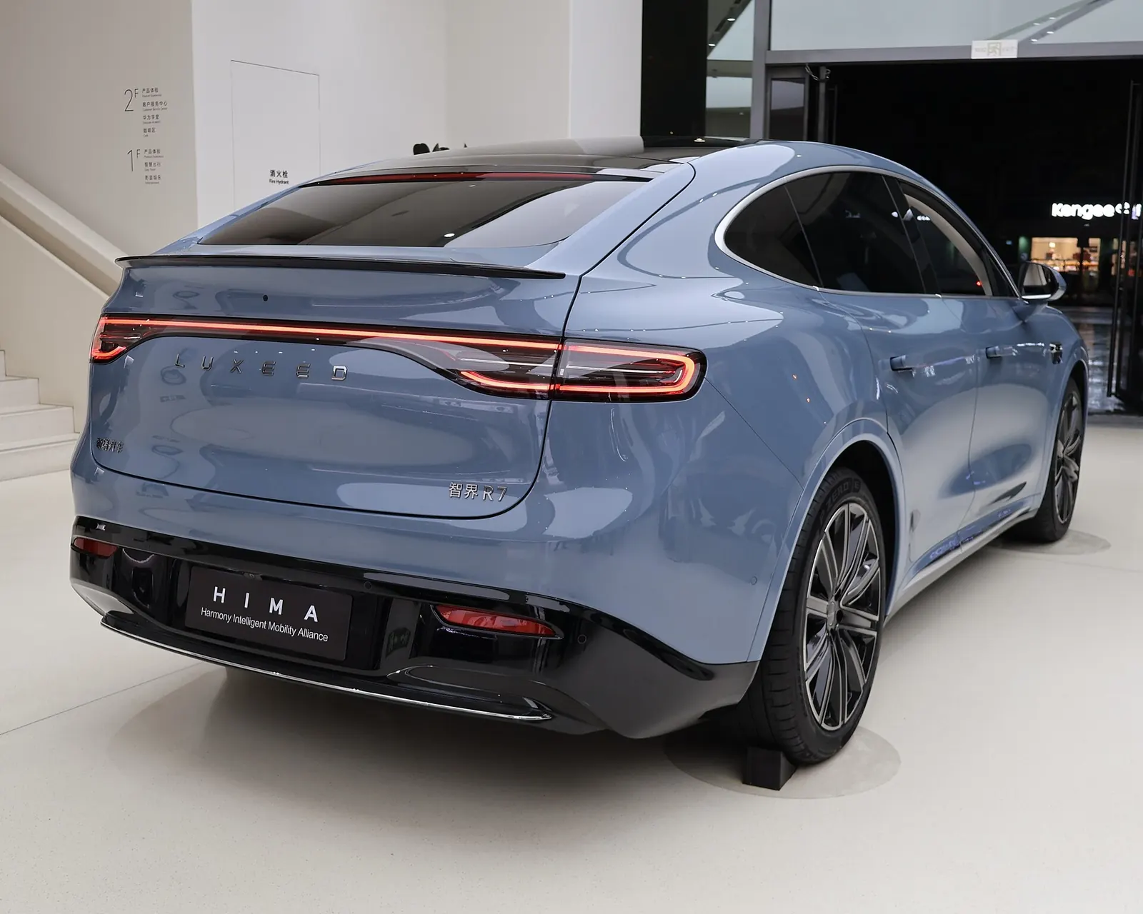 Rear three-quarter view of a blue Luxeed R7 with the ducktail spoiler and full-width tail-light bar