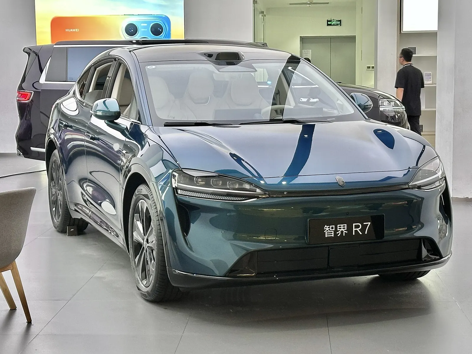 Front three-quarter view of a teal Luxeed R7 in a showroom