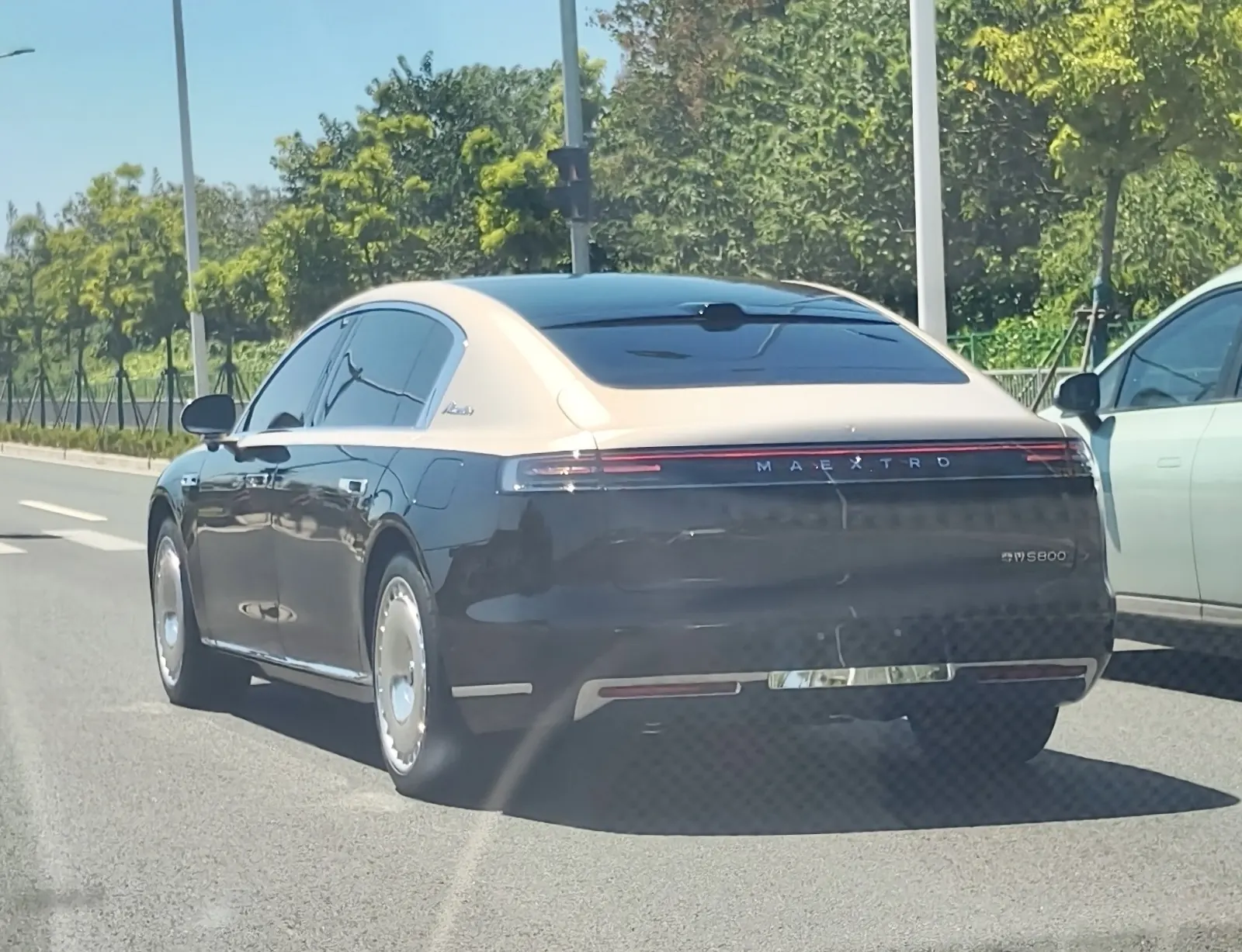 منظر ثلاثي الأرباع من الخلف لسيارة Maextro S800 سوداء وذهبية على الطريق