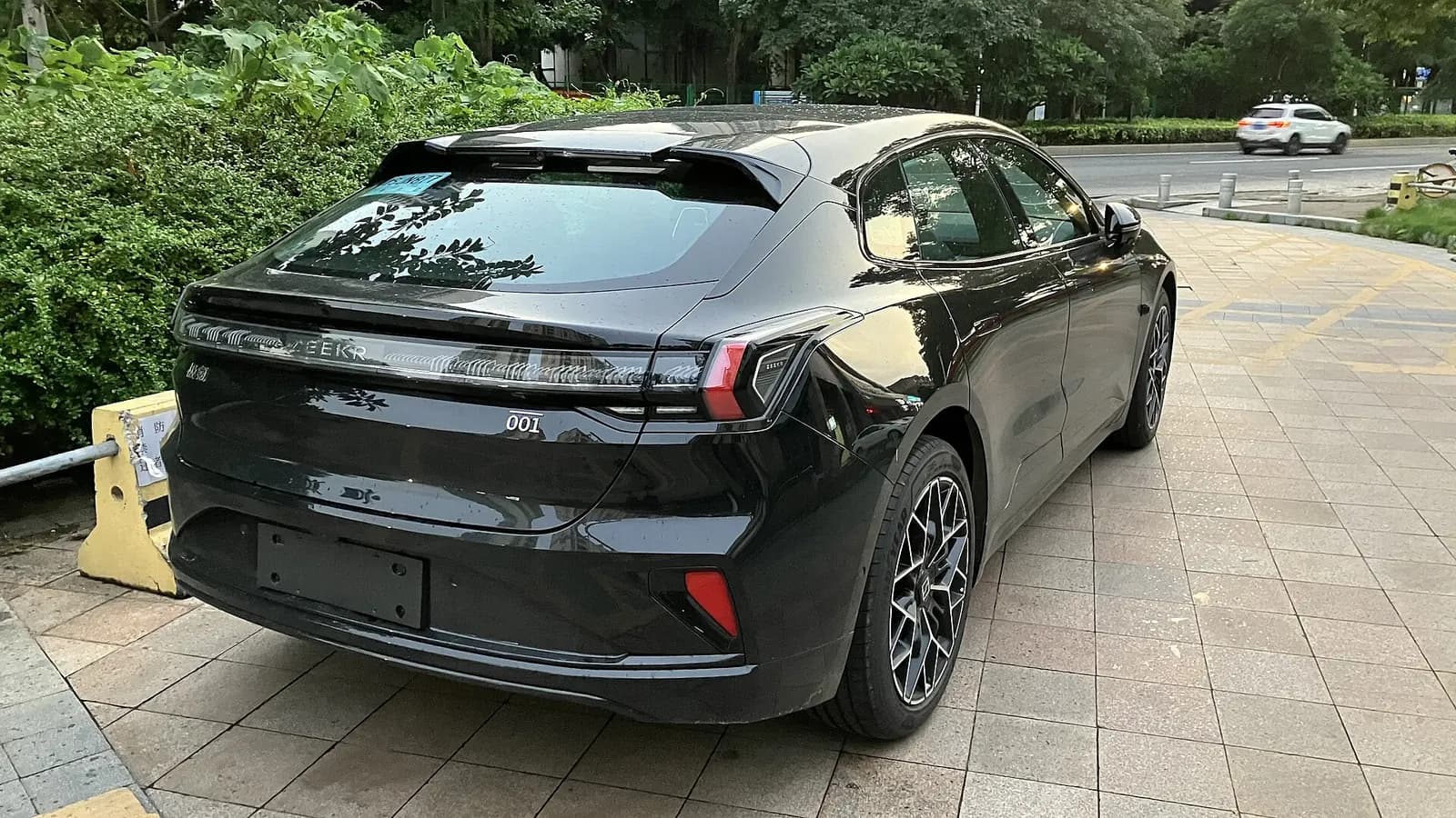 Black Zeekr 001 seen from the rear and side, showing the tail-lamp strip and 001 badge