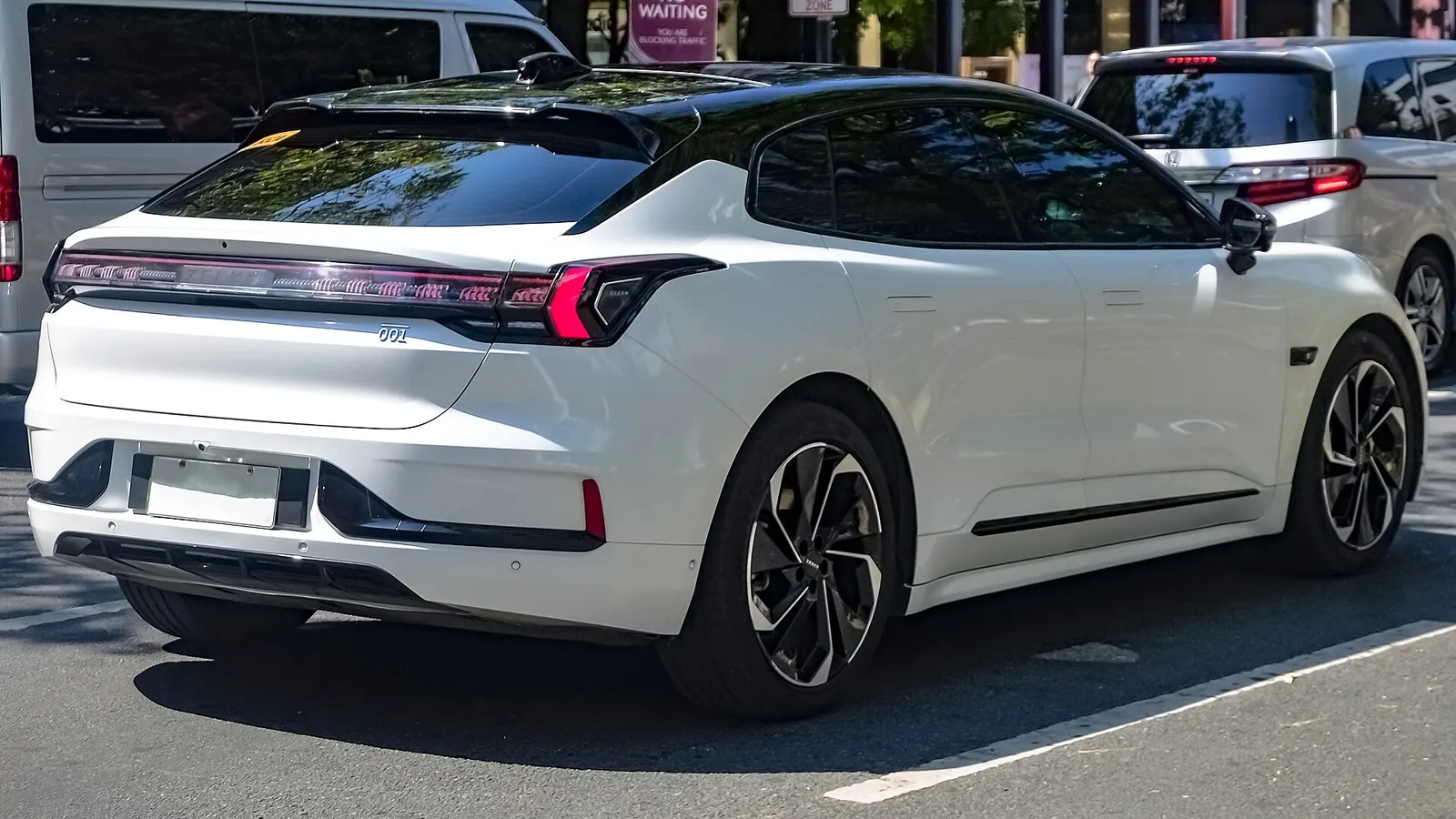 Rear three-quarter view of a white Zeekr 001 showing the light bar and roof spoiler